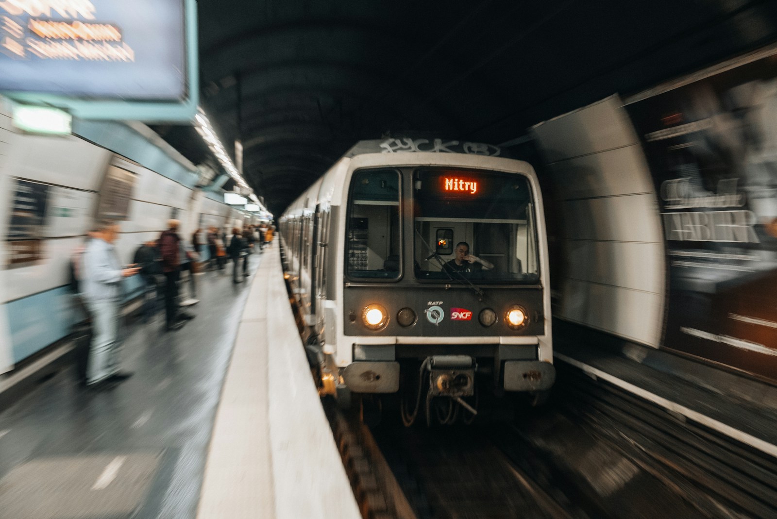 Photo by Nejc Soklič a train traveling through a train station next to a crowd of people